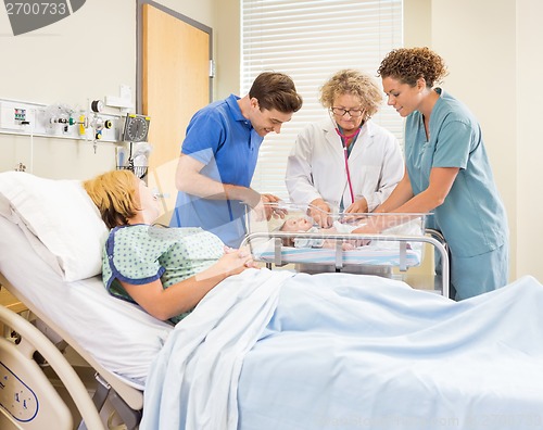 Image of Doctor Examining Babygirl While Parents And Nurse Looking At Her