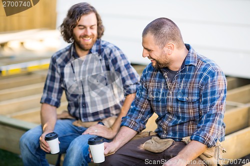 Image of Construction Workers Holding Disposable Coffee Cups On Wooden Fr