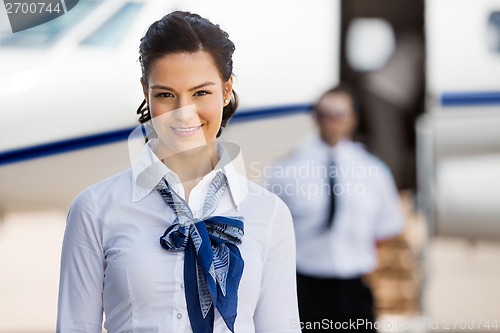 Image of Pretty Stewardesses Smiling With Pilot And Private Jet In Backgr