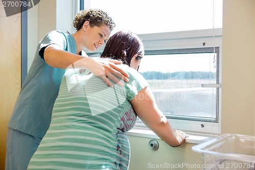 Image of Nurse Comforting Tensed Pregnant At Window In Hospital Room