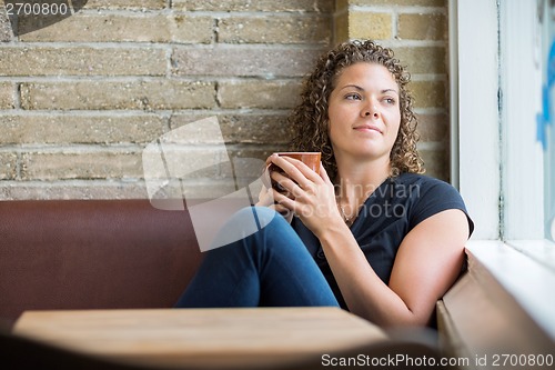 Image of Thoughtful Woman Holding Coffee Mug In Cafe