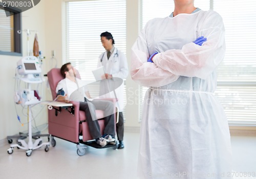 Image of Nurse Standing Arms Crossed While Doctor Examining Patient's Hea