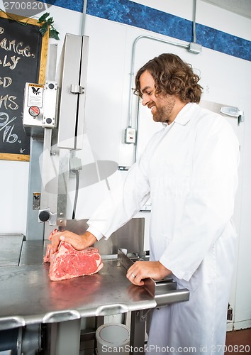 Image of Smiling Butcher Slicing Meat In Machine