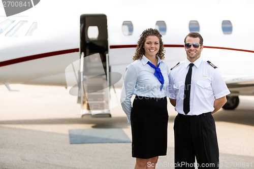 Image of Airhostess And Pilot Standing Against Private Jet