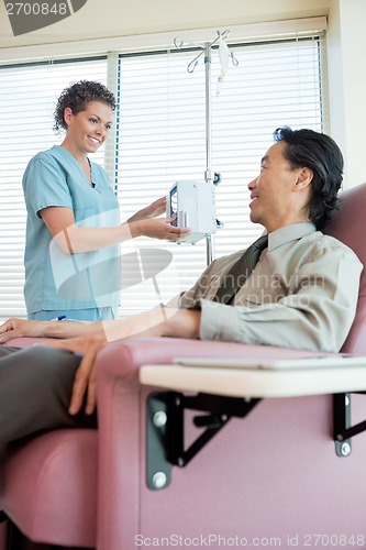 Image of Nurse Looking At Patient While Operating IV Machine