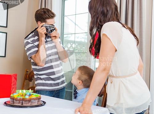 Image of Man Taking Picture Of Family At Birthday Party