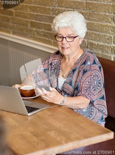 Image of Woman Text Messaging Through Smartphone In Cafe