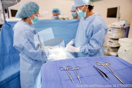 Image of Surgical Tools On Stand With Doctors Operating Patient