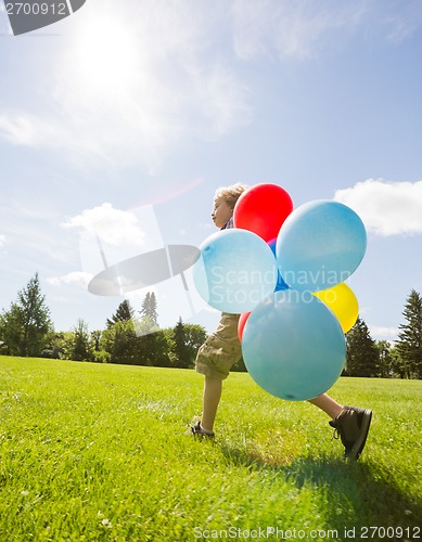 Image of Boy With Helium Balloons Walking In Park