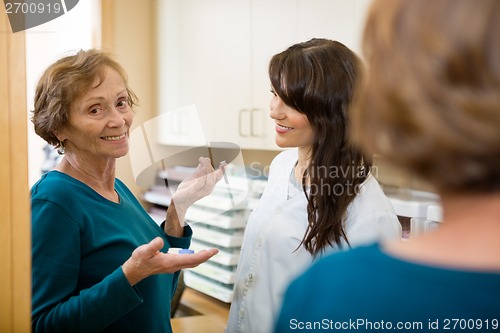 Image of Optometrist Looking At Woman Holding Contact Lens