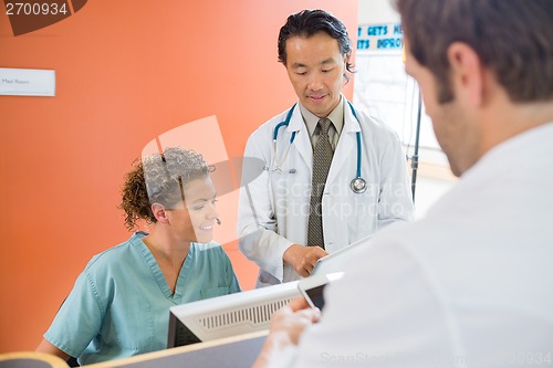 Image of Medical Team Using Digital Tablet While Patient Standing At Rece