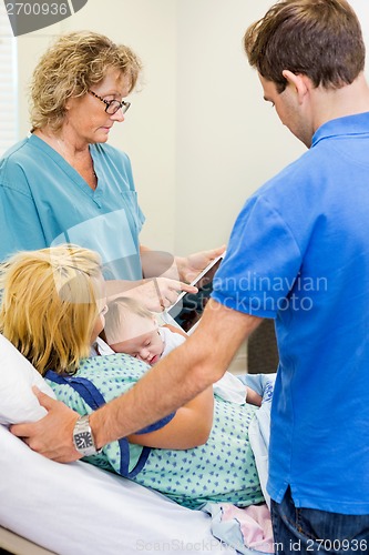 Image of Nurse Explaining Reports On Tablet To Couple With Babygirl