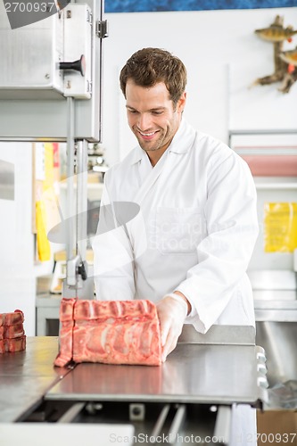 Image of Butcher Slicing Meat On Bandsaw In Shop