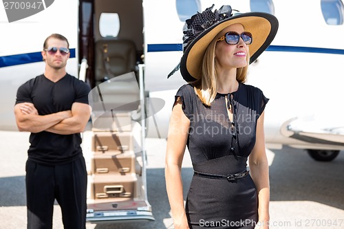 Image of Happy Woman With Bodyguard And Private Jet In Background