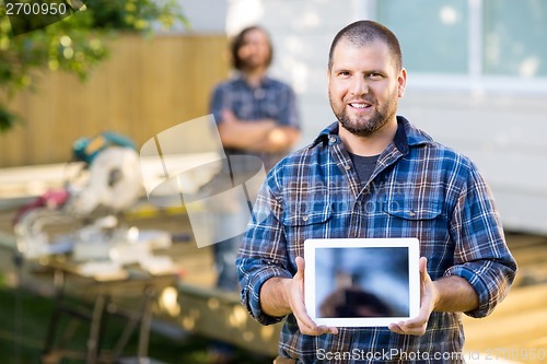 Image of Carpenter Displaying Digital Tablet With Coworker In Background