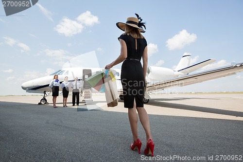 Image of Woman Carrying Shopping Bags While Walking Towards Private Jet