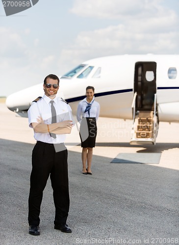 Image of Full Length Pilot Against Stewardess And Private Jet At Terminal