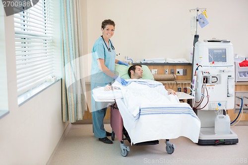 Image of Nurse Standing By Patient Receiving Dialysis In Hospital