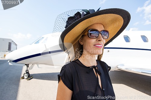 Image of Rich Woman Standing Against Private Jet