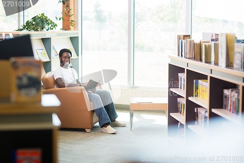 Image of Smiling Student Reading Book In Library