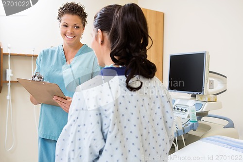 Image of Nurse Writing Notes With Patient In Ultrasound Room