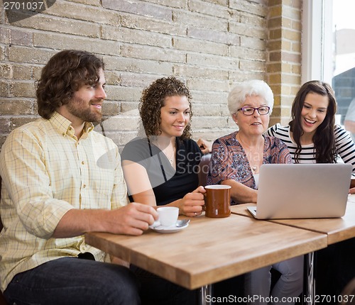 Image of Woman With Friends Using Laptop At Cafe Table