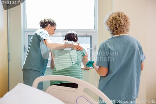 Image of Nurse Carrying Hospital Gown For Worried Pregnant Woman