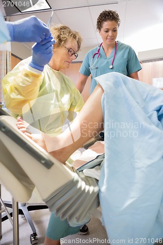 Image of Surgeon Receiving Scissors From Colleague While Delivering Baby