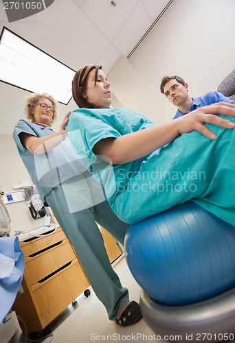 Image of Nurse Assisting Pregnant Woman Sitting On Exercise Ball