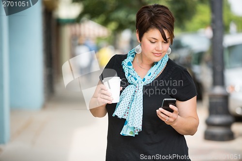 Image of Woman Holding Coffee Cup While Messaging Through Smartphone