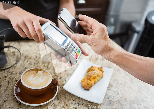 Image of Customer Paying Through Mobilephone Over Electronic Reader At Ca