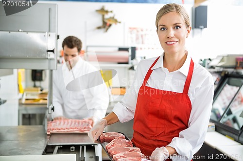 Image of Smiling Butcher Holding Meat Tray At Store