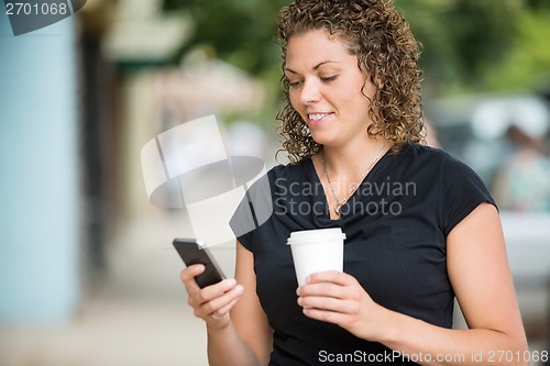 Image of Woman With Coffee Cup Messaging Through Smartphone