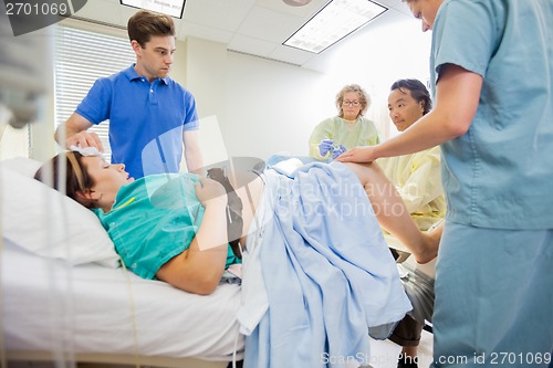 Image of Man Looking At Doctor Delivering Baby