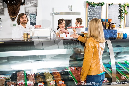 Image of Saleswoman Giving Meat To Female Customer