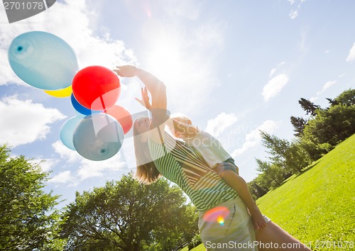 Image of Mother And Daughter Holding Balloons In Park