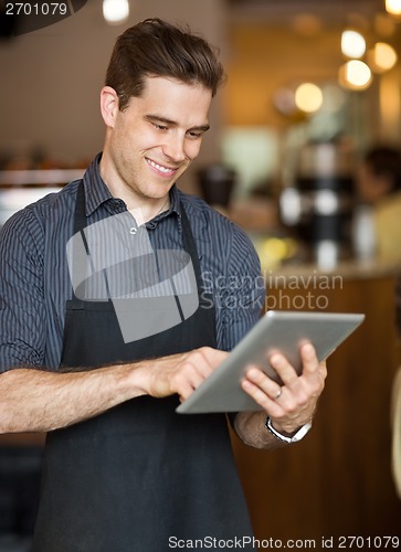 Image of Male Owner Using Digital Tablet In Cafeteria