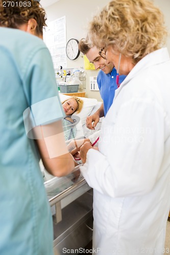 Image of Medical Team With Couple Looking At Baby In Hospital