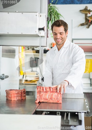 Image of Butcher Cutting Meat On Bandsaw