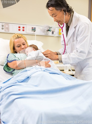 Image of Doctor Examining Babygirl Sleeping In Mother's Arms