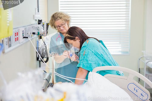 Image of Pregnant Woman Breathing Through Oxygen Mask While Nurse Assisti