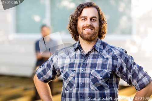 Image of Manual Worker Smiling While Coworker Standing In Background