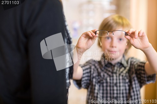 Image of Boy Holding Spectacles With Mother In Foreground At Shop