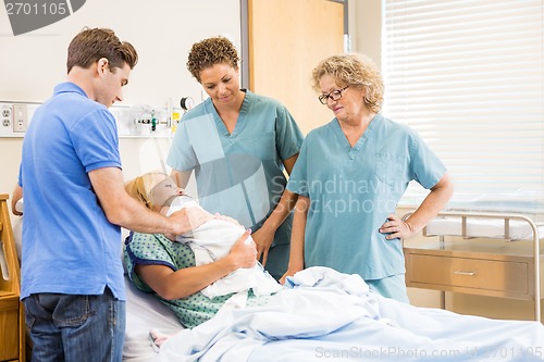 Image of Nurses And Man Looking At Newborn Baby Sleeping On Mother