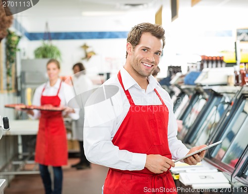 Image of Portrait Of Happy Butcher Holding Digital Tablet At Store