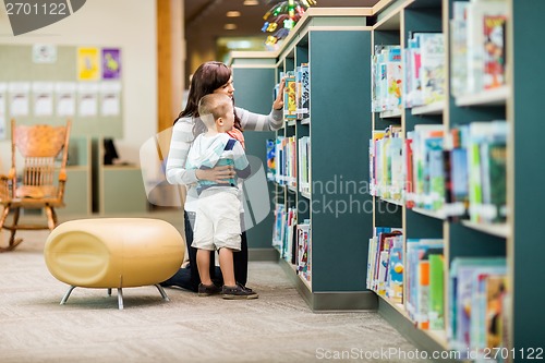 Image of Teacher And Boy Selecting Book In Library