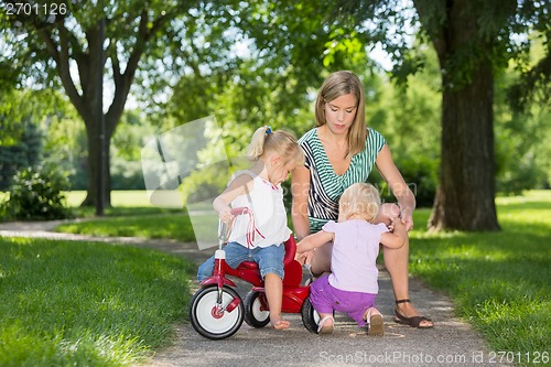 Image of Mother And Children With Tricycle In Park