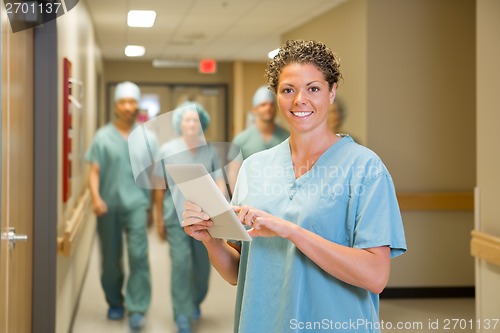 Image of Surgeon Holding Digital Tablet In Hospital Corridor