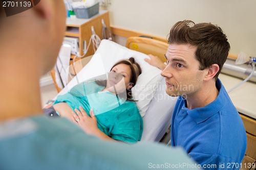 Image of Man And Pregnant Woman Listening To Nurse In Hospital