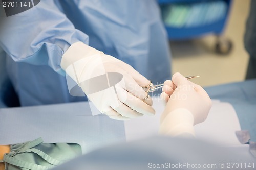 Image of Surgeons Passing Surgical Scissors During Surgery